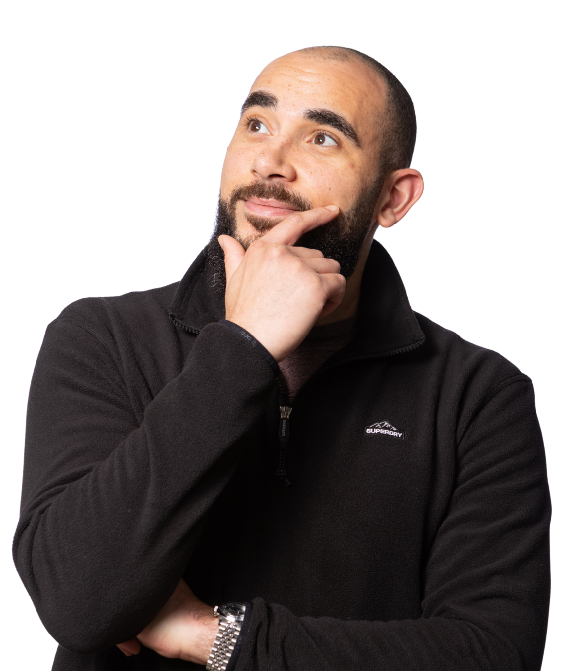 A man with a beard, wearing a black quarter-zip fleece jacket and grey pants, has his hand on his chin and is looking upwards thoughtfully.