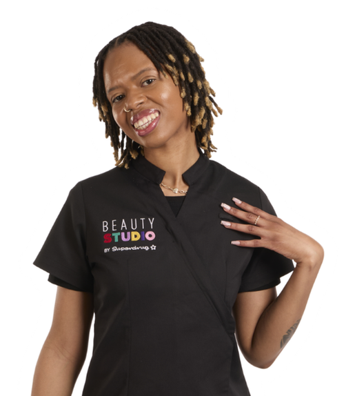 A smiling woman with dreadlocks and a black uniform with "BEAUTY STUDIO" logo stands on a white background.